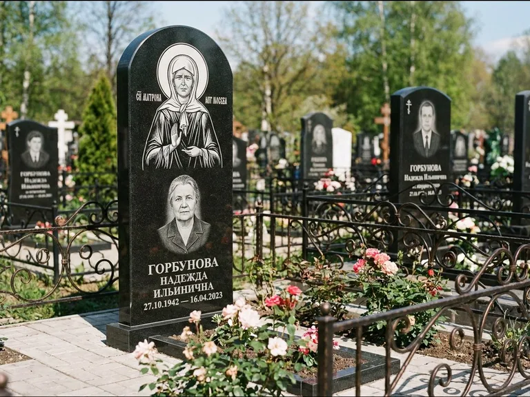 Памятник с гравировкой иконы: стела с арочным верхом и киотом под образ — гравировка образа Матроны Московской, гранитный цоколь с тёмной плиткой, работа «Ковалёв» в Воронеже