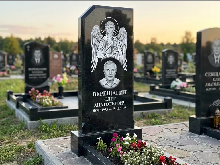 Памятник с гравировкой иконы: стела с резным навершием и нимбом в золоте — гравировка образа Спасителя, высокие разросшиеся туи полукругом, работа «Мельникова» в Воронеже