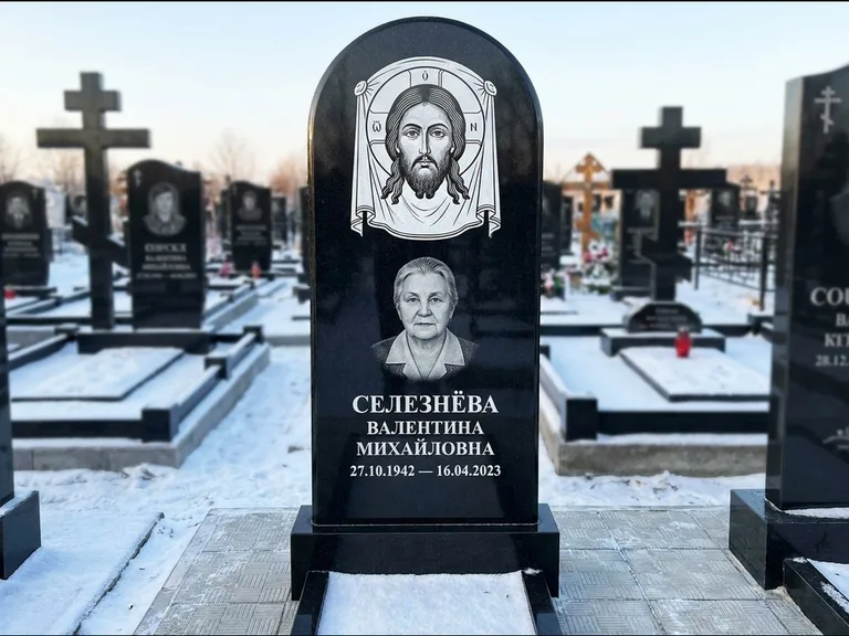 Памятник с гравировкой иконы: небольшая скромная одиночная стела с именной иконой — золочёный нимб на образе, аккуратный участок с газоном, работа «Ковалёв» в Воронеже