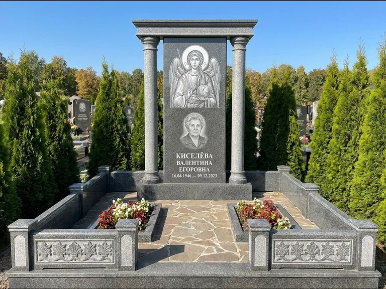 Памятник с гравировкой иконы: массивная стела с двускатным навершием-домиком — гравировка Николая Чудотворца, живая изгородь из туи, работа «Журавлёв» в Воронеже