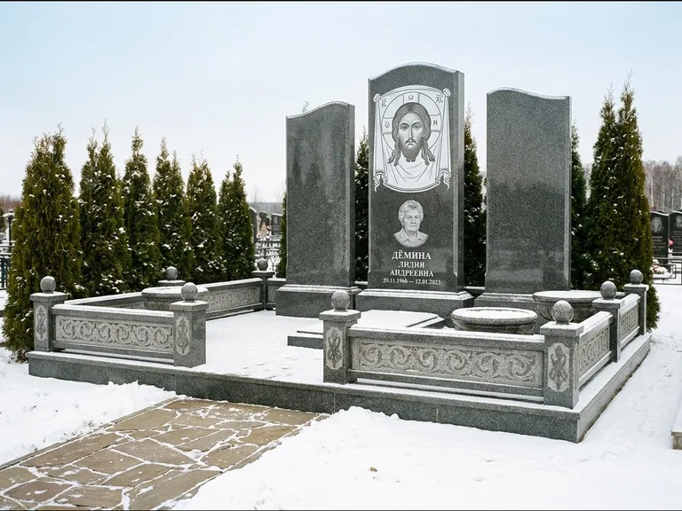 Памятник с гравировкой иконы: узкая вертикальная стела-пилон с ликом — икона в резной рамке-киоте, открытая лужайка без ограды, работа «Одинцов» в Воронеже