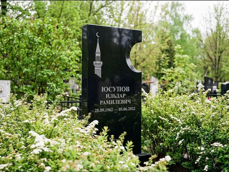 Мусульманский памятник с гравировкой мечети: стела с боковым вырезом в форме полумесяца — гравировка минарета с полумесяцем, низкие кусты спиреи в цвету, работа «Юсупов» в Воронеже