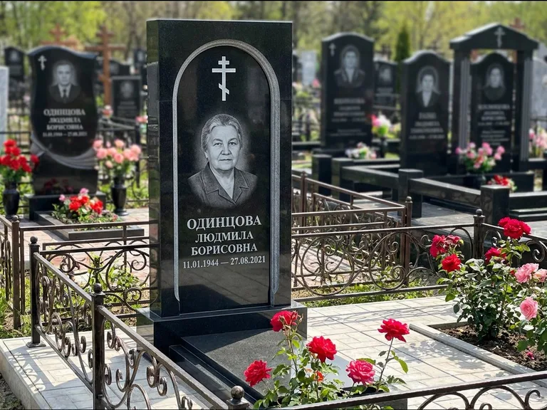 Памятник из чёрного гранита — скромная невысокая стела с крестом с терновым венцом, работа «Лаврентьева» в Воронеже