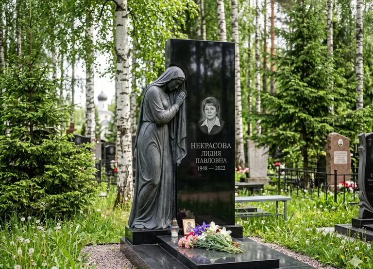 Гранитная фигура скорбящего мужчины у чёрной стелы в Воронеже